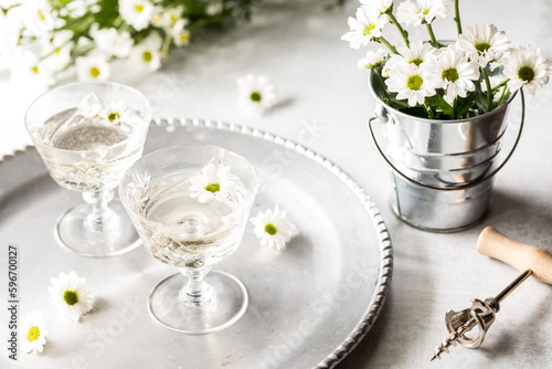 A beautiful scene of glasses of white wine with white daisy flowers, photo