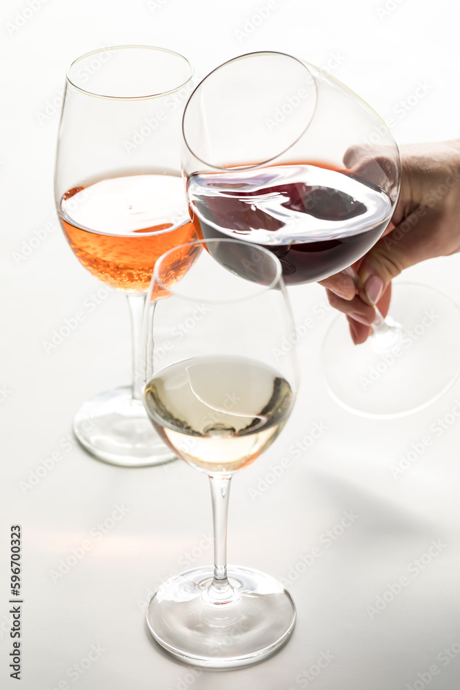 Glasses of red, white and rose wine with a hand holding the red wine.