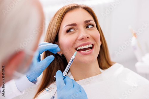 Dentist applying local anesthetic to female patient
