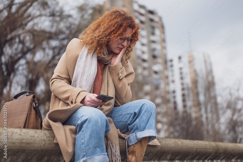 Natural portrait of a caucasian ginger woman with freckles and curly hair. She is depressed. Natural portrait of a caucasian ginger woman with freckles and curly hair. She is depressed.