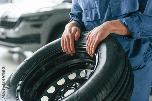 Tire replacement concept. Man in blue uniform is working in the car service © standret