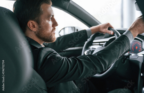 Driving the car. Man in formal business clothes is sitting in the modern automobile