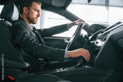 Man in formal business clothes is sitting in the modern automobile