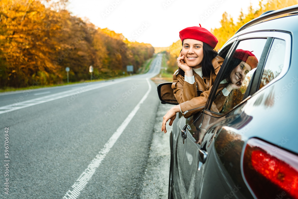 Naklejka premium A woman peers out of the window of a car on the roadside in autumn