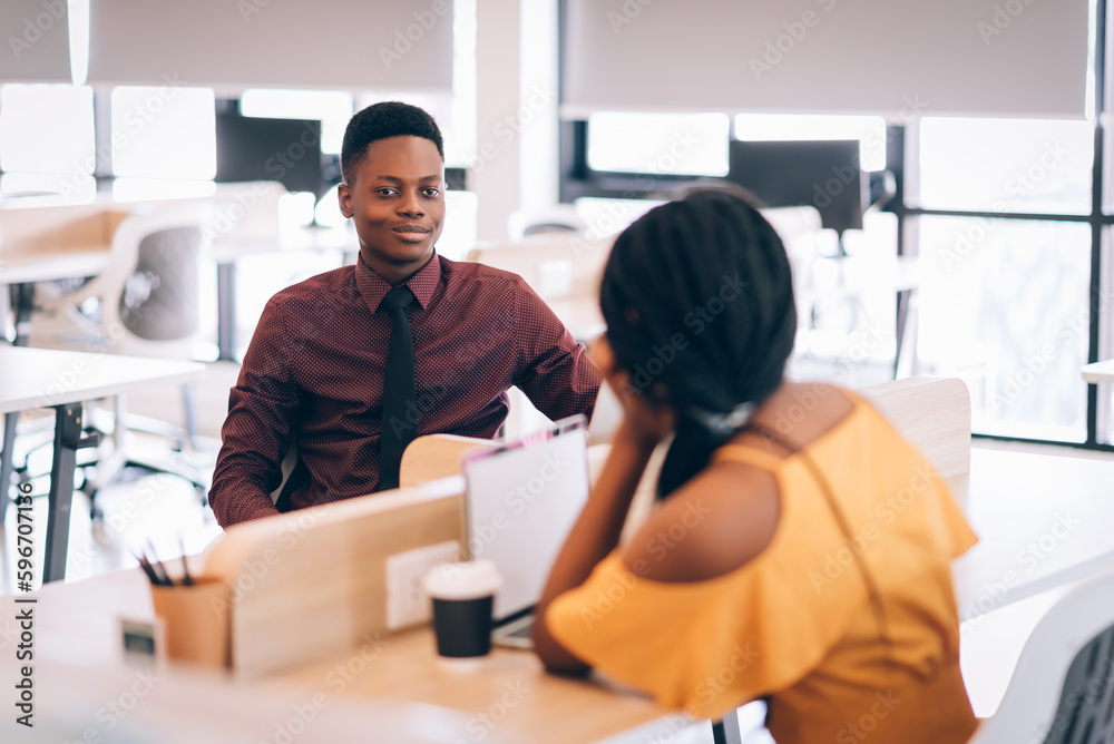 Fototapeta premium Two young african american business people working together in co-working space with happy together
