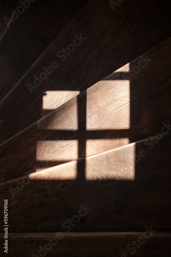 Dark wooden stairs, on which light shines through the window. Minimalist photo.