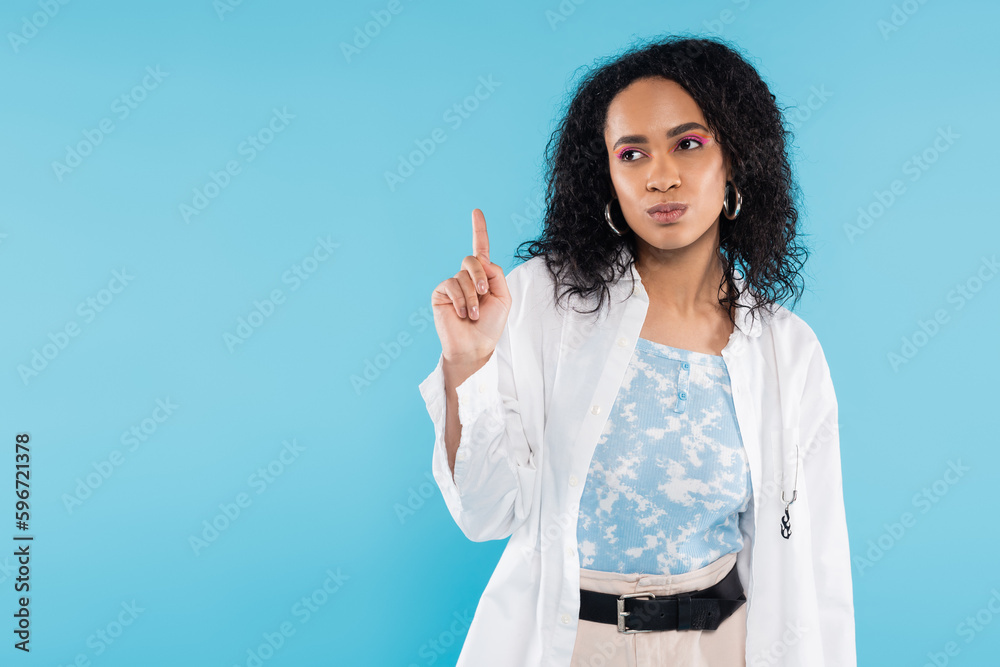 thoughtful african american woman in white shirt showing idea sign isolated on blue. thoughtful african american woman in white shirt showing idea sign isolated on blue.