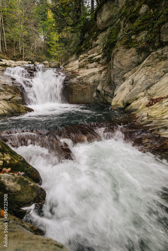 Vertical view of autumnal waterfall in a small rocky river. Motion water.