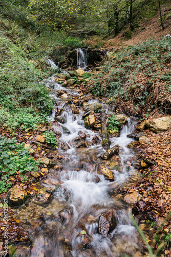 Vertical view of autumnal waterfall in a small stream. Motion water.
