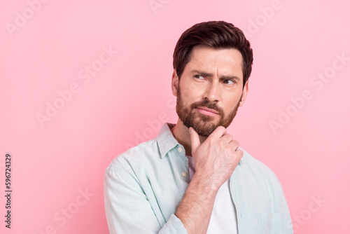 Photo portrait of nice young male look skeptical empty space touch chin dressed stylish blue garment isolated on pink color background