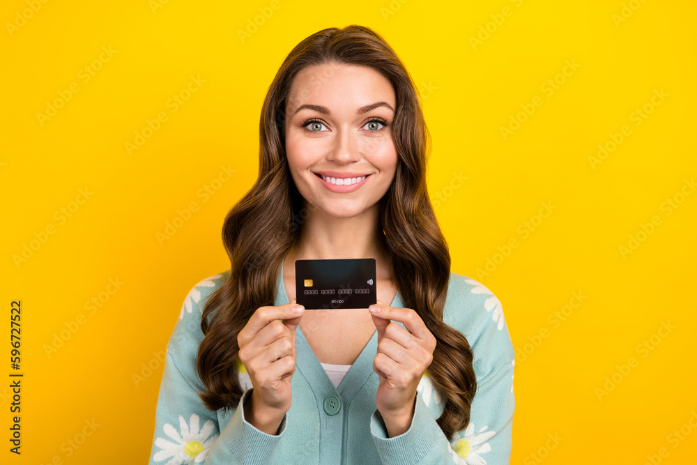 Photo advert of young cheerful lady promoter hold black premium plastic card demonstrate wireless nfc option isolated on yellow color background Photo advert of young cheerful lady promoter hold black premium plastic card demonstrate wireless nfc option isolated on yellow color background