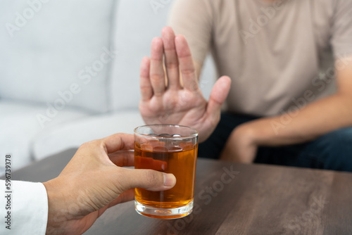 man refuses say no and avoid to drink an alcohol whiskey , stopping hand sign male, alcoholism treatment, alcohol addiction, quit booze, Stop Drinking Alcohol. Refuse Glass liquor, unhealthy, reject photo