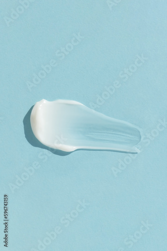 White cream texture on a blue background. A smear of a cosmetic skin care product. Wellness and beauty concept. Top view.