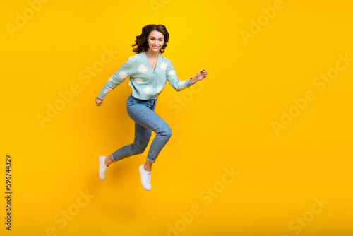 Full length photo of young active model funny girl running jumping fast speed demonstrate her new stylish outfit isolated on yellow color background © deagreez