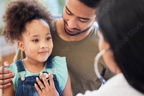 My doctor is really nice. Shot of a little girl sitting on her fathers lap while being examined by her doctor.