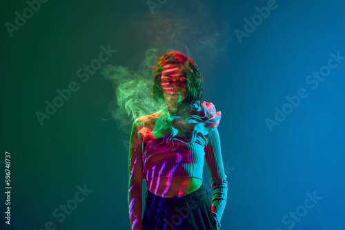 Portrait of stunning girl woman standing with closed eyes surrounded by smoke over neon blue and green gradient background