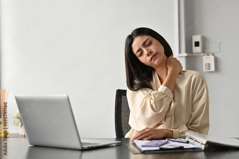 A female office worker feels a tense pain in her shoulder due to sitting at work for a long time or sitting in the wrong posture. A female office worker feels a tense pain in her shoulder due to sitting at work for a long time or sitting in the wrong posture.