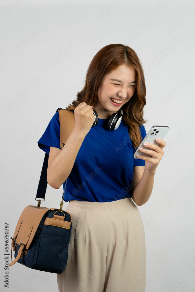 Asian female student shoulder bag, wear headphones, hold smart phones phone on white background Asian female student shoulder bag, wear headphones, hold smart phones phone on white background