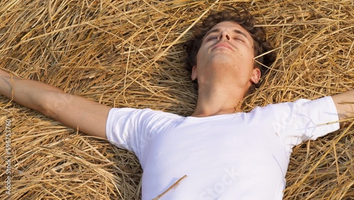 young guy in white shirt lies in a field with wheat