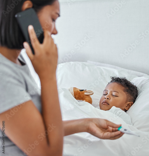 .. Shot of a woman taking her little boys temperature with a thermometer in bed at home.