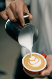 Barista making latte art in a cafe Male hands pouring steam of milk into a cup of Cappuccino with a pattern