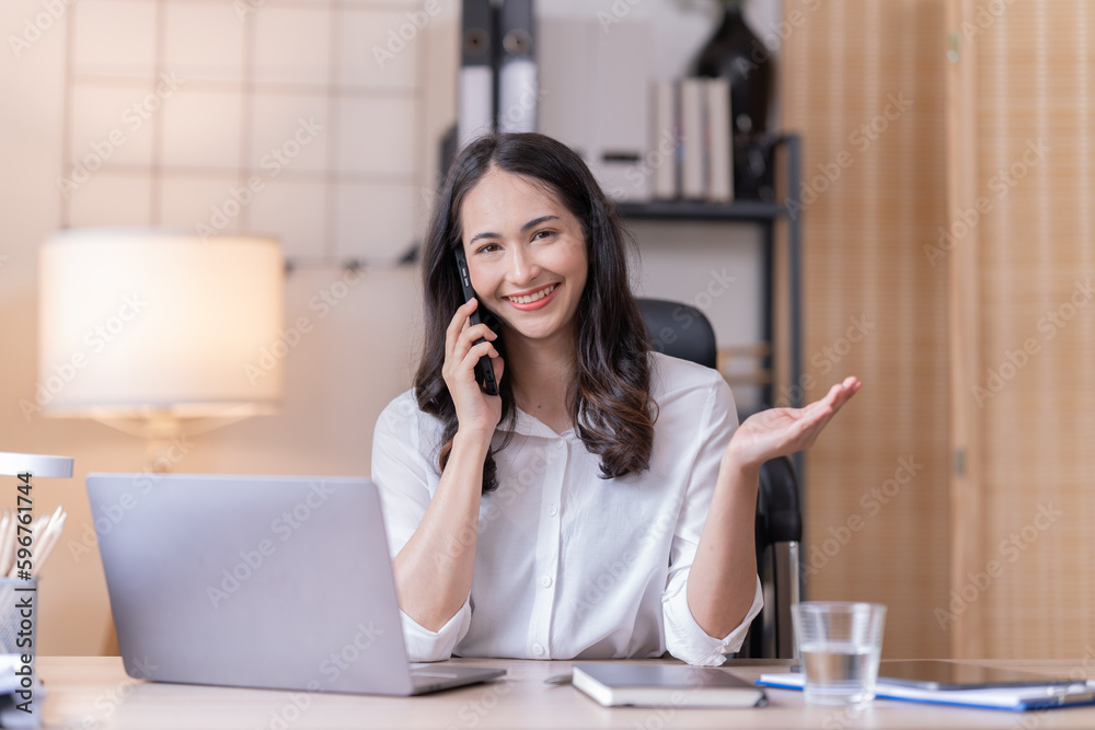 Young happy businesswoman working with tablet and mobile phone in corporate office.