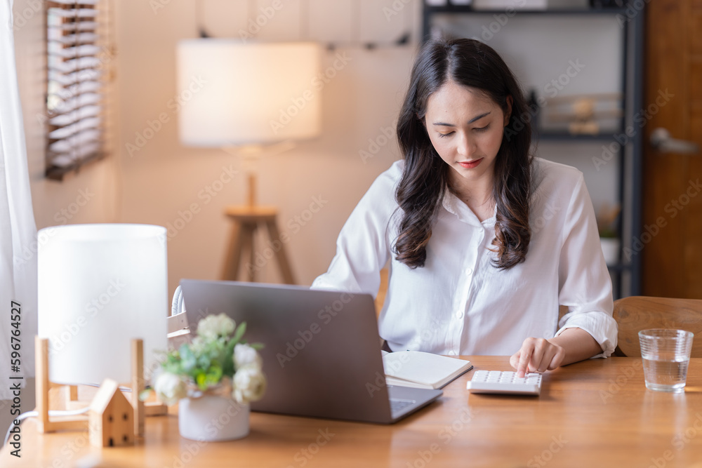 Attractive happy young Asian businesswomen at home, sitting at the desk, using a laptop computer, tablet and headphones having a video chat. Attractive happy young Asian businesswomen at home, sitting at the desk, using a laptop computer, tablet and headphones having a video chat.