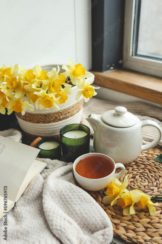 Cup of tea, candles, basket with daffodils, spring aesthetic photo