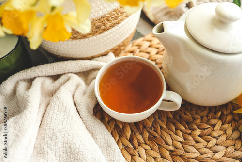 Cup of tea, candles, basket with daffodils, spring aesthetic photo