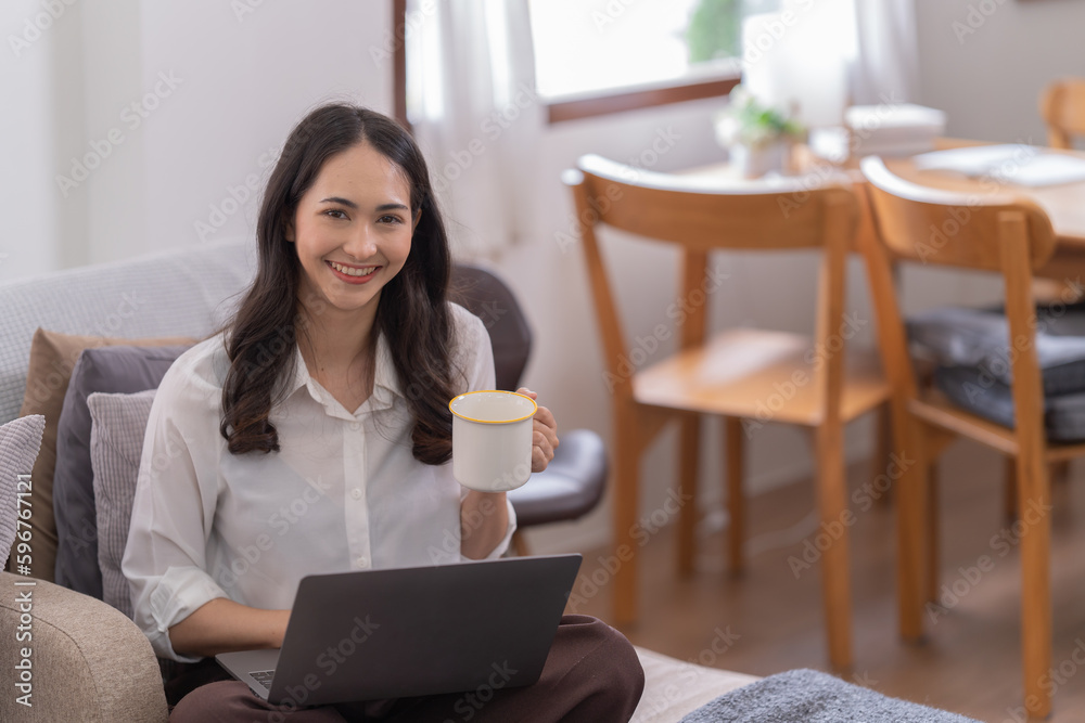 Full length photo of positive business girl sits floor legs crossed folded work remote laptop read document report hold mug beverage in house Full length photo of positive business girl sits floor legs crossed folded work remote laptop read document report hold mug beverage in house