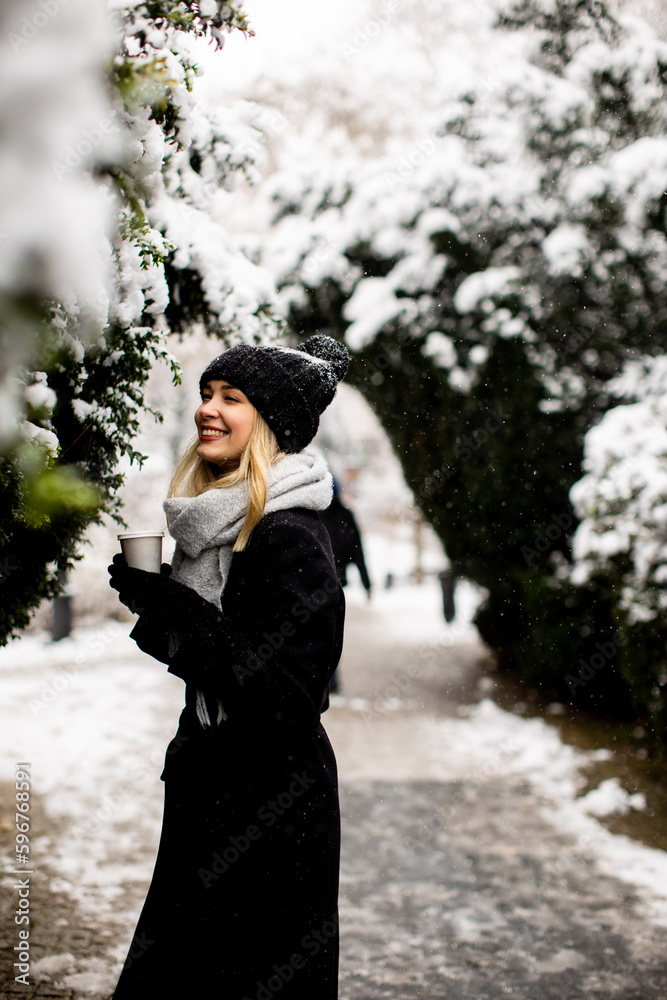 Young woman in warm clothes enjoying in snow with takeaway coffee cup Young woman in warm clothes enjoying in snow with takeaway coffee cup