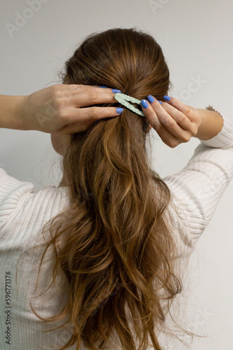 Young woman clipping her blond hair with a snap hair clip