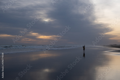 Niño saludando en la playa a la distancia durante el atardecer
