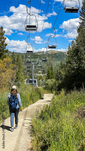 woman walking the path below the ski lifts up the mountain in the summer photo