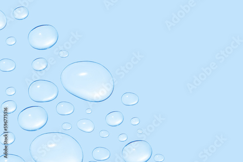 Drops of transparent gel or water in different sizes. On a blue background.