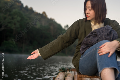 solo asian woman travel by thai local bamboo boat in tropical forest and lake in autumn season