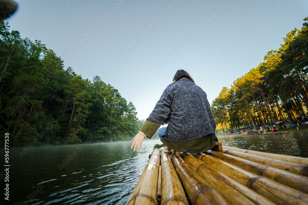 solo asian woman travel by thai local bamboo boat in tropical forest and lake in autumn season