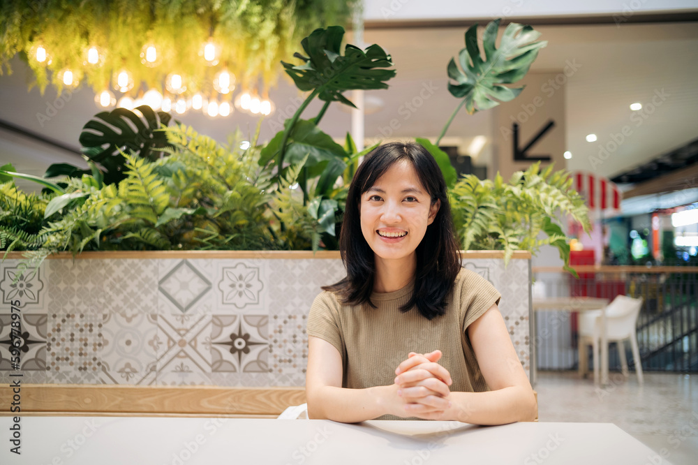 Smiling beautiful asian woman sitting in cafeteria at shopping mall. Smiling beautiful asian woman sitting in cafeteria at shopping mall.