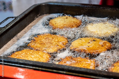 Delicious tasty potato pancakes frying in hot oil, Polish placki ziemniaczane detail, closeup, nobody. Food cooking on a large pan, soft focus, preparing greasy meals dishes, frying in oil concept