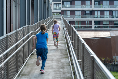 Two elementary school age girls, children running through the city alone, two people, kids running around on their own, urban location city streets simple lifestyle shot, freedom, independence concept