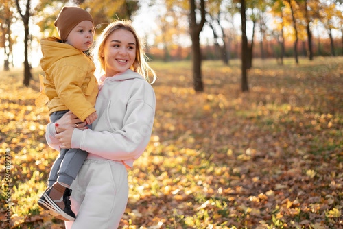 Happy family mother and child boy on a walk in the autumn leaf fall in park