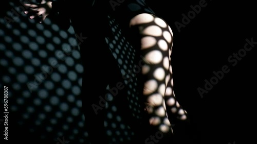 gorgeous slender woman in black bodysuit dancing seductively in darkness, back view, sexy ass