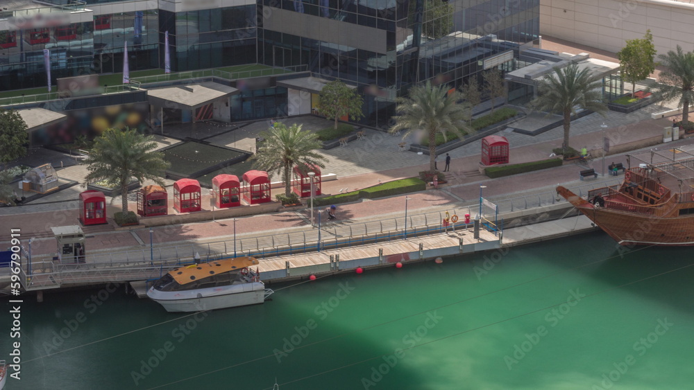 Dubai marina promenade on waterfront along canal aerial timelapse.