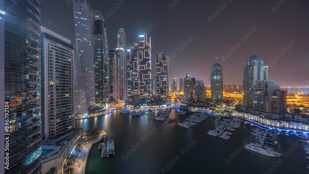 Fototapeta premium Dubai marina tallest skyscrapers and yachts in harbor aerial all night timelapse.
