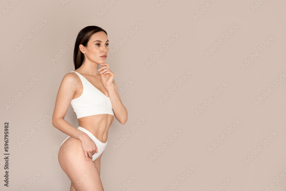 Beautiful woman posing on beige background in underwear, copy space Beautiful woman posing on beige background in underwear, copy space