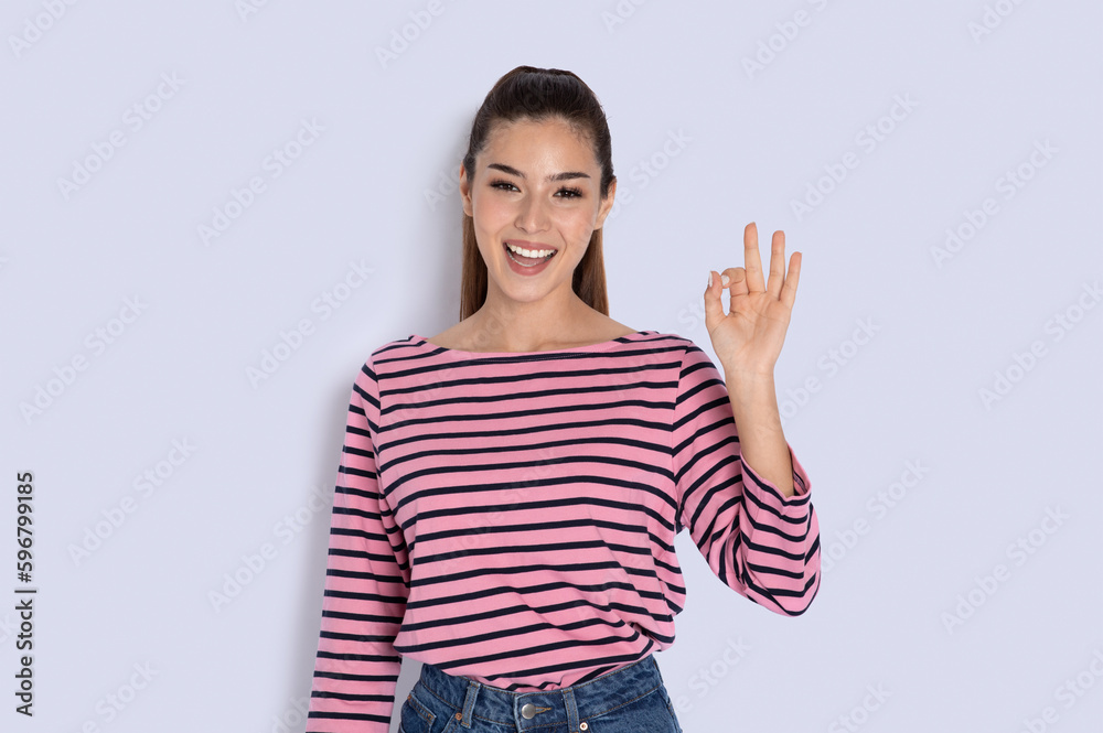 Positive latin young woman showing okay gesture on grey Positive latin young woman showing okay gesture on grey