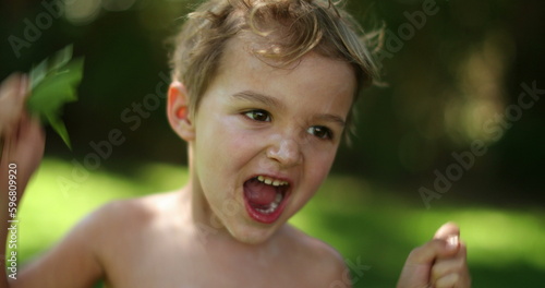 Happy excited infant toddler child jumping up and down outdoors. Kid receiving news feeling joy