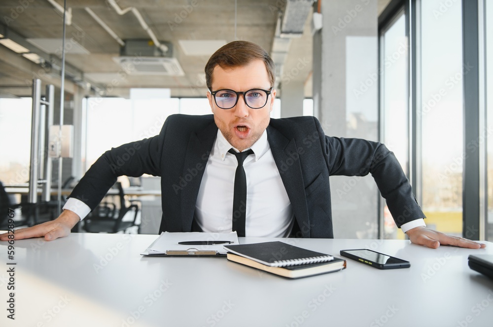 Angry senior businessman sitting at his desk and screaming Angry senior businessman sitting at his desk and screaming