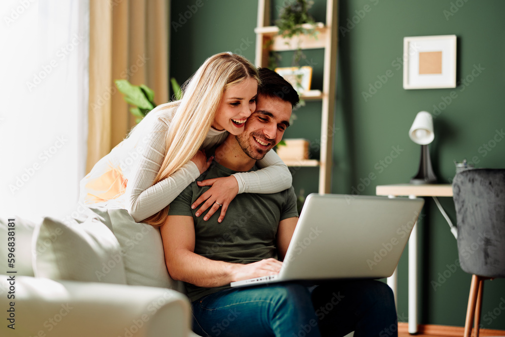 Fototapeta premium Beautiful young happy couple having video call via laptop at home