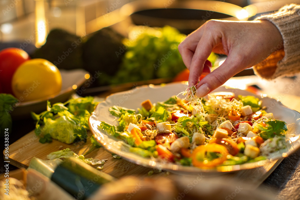 Young adult woman preparing a healthy salad in the kitchen